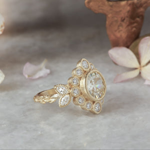 Gold ring with a diamond on a marble surface with dried flowers